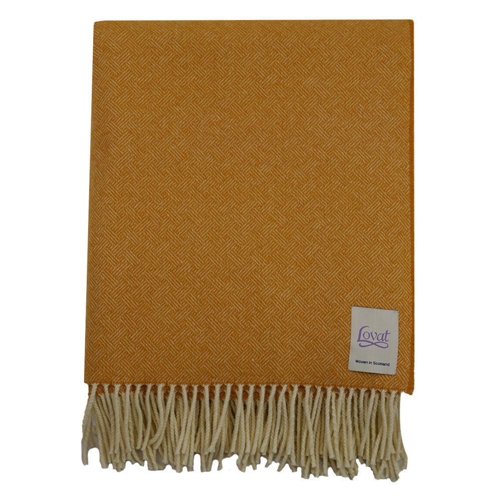 A folded 100% lambswool diamond border blanket in harvest yellow with fringing, displayed on a neutral background.