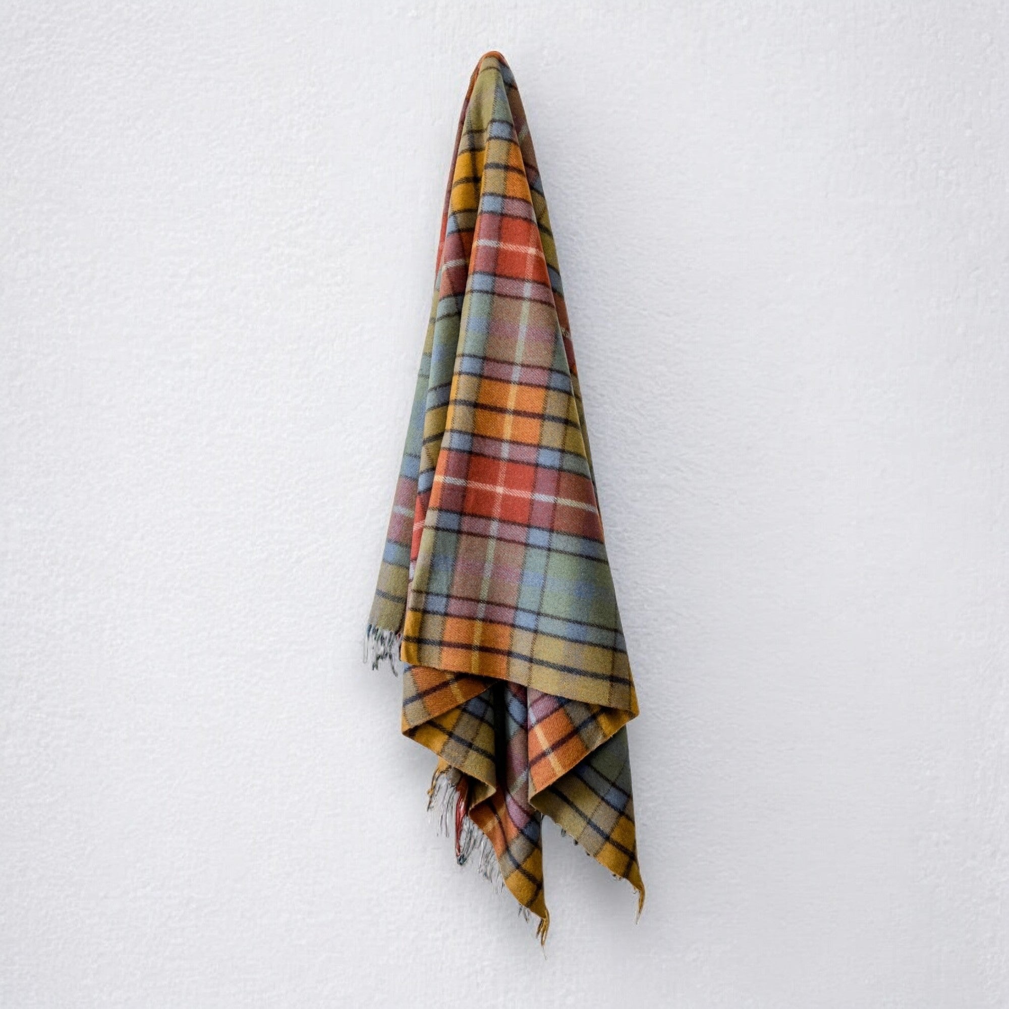 A Buchanan clan tartan blanket with fringing, hanging against a white background.
