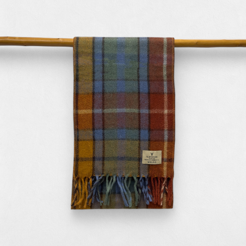 A antique buchanan scarf with fringes, displayed on a wooden rod against a white background.