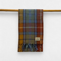 A antique buchanan scarf with fringes, displayed on a wooden rod against a white background.