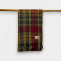 A autumn buchanan scarf hanging on a wooden rod against a white background, with a small label visible on the lower side.
