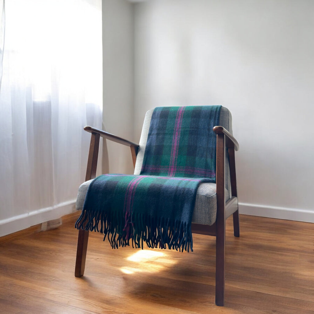 A baird tartan knee blanketdraped over a chair in a cosy room