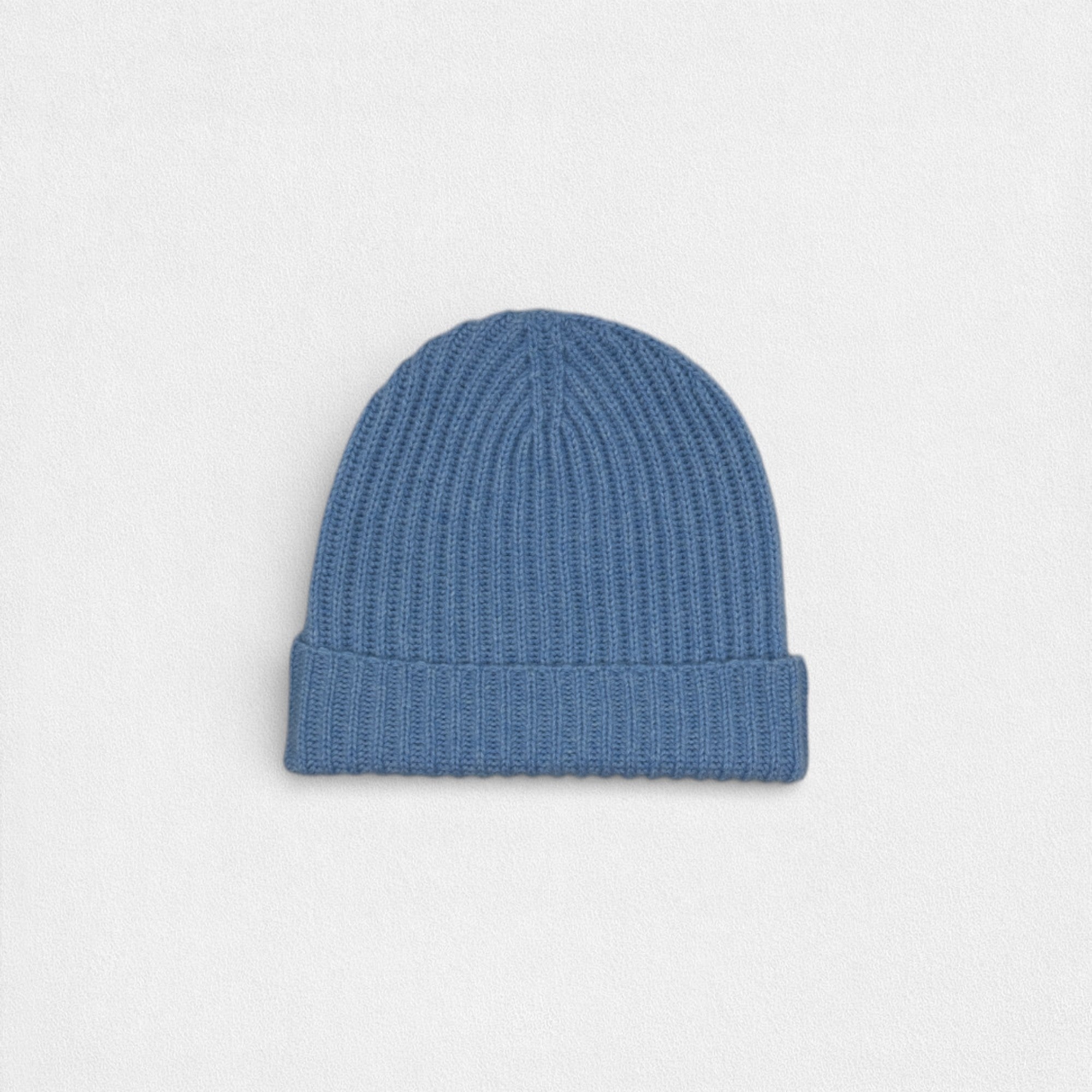 Blue cashmere ribbed beanie on white background.