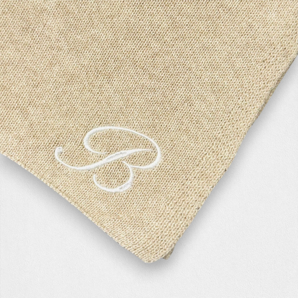 A close up of the Ballantines Script embroidery on the corner of the natural cream cashmere blanket