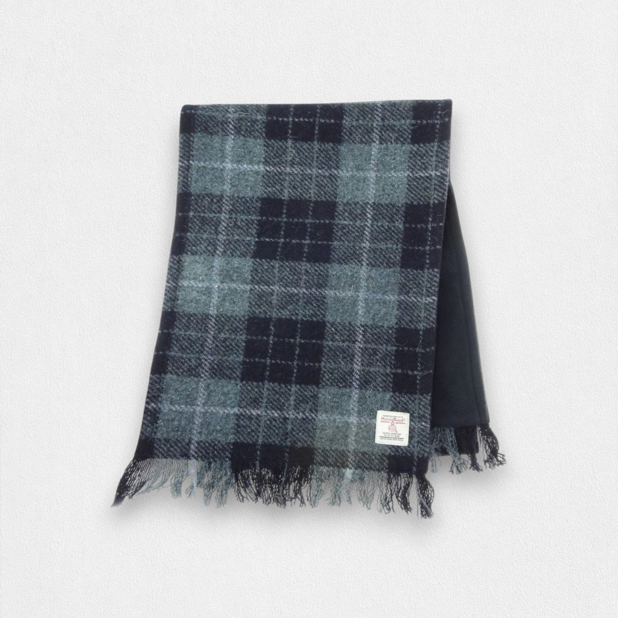 A grey and black check Harris Tweed scarf with fringing, displayed on a plain background.