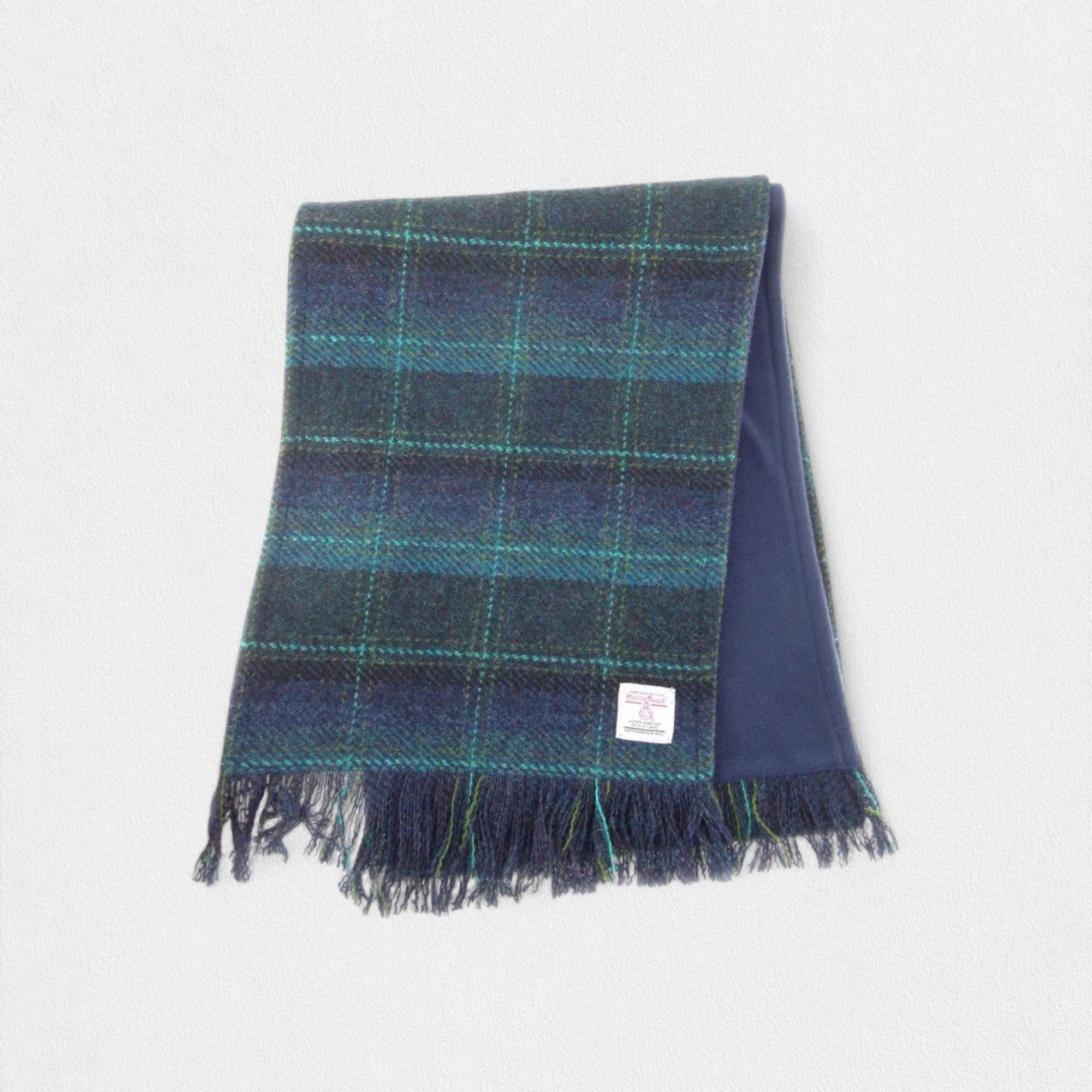 A Harris Tweed scarf with a turquoise check pattern, featuring fringes on the edges and a label showing the brand name.