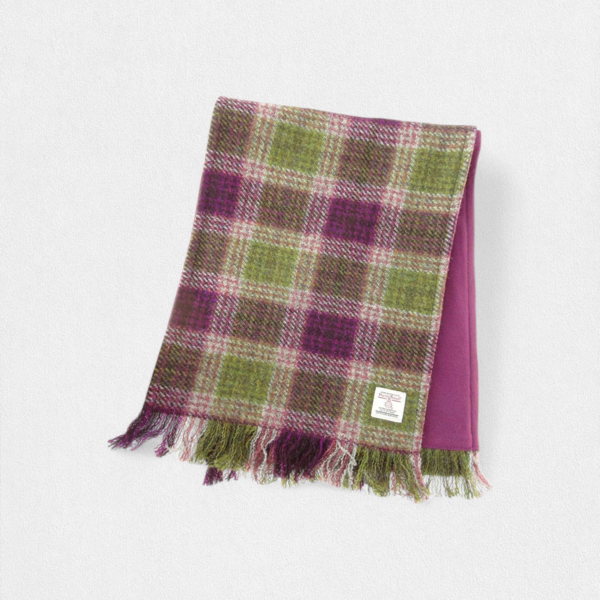A Harris Tweed scarf with a heather pattern, featuring soft, muted tones in purple and green, with fringing at the ends.