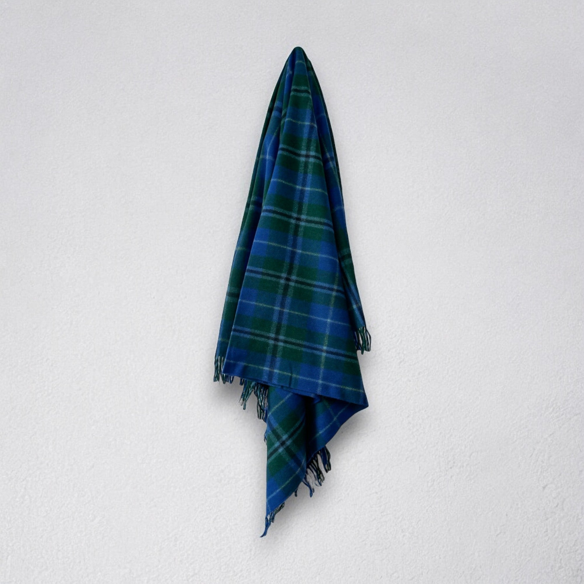 a 100% recycled blanket in douglas tartan hanging from a wall hook on a white background 