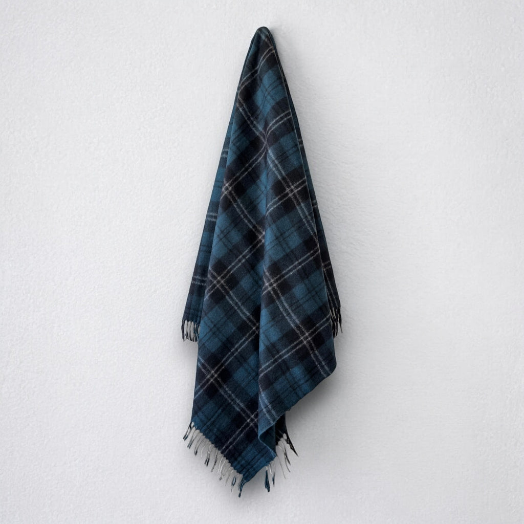 a 100% recycled blanket in ramsay blue tartan hanging from a wall hook on a white background 