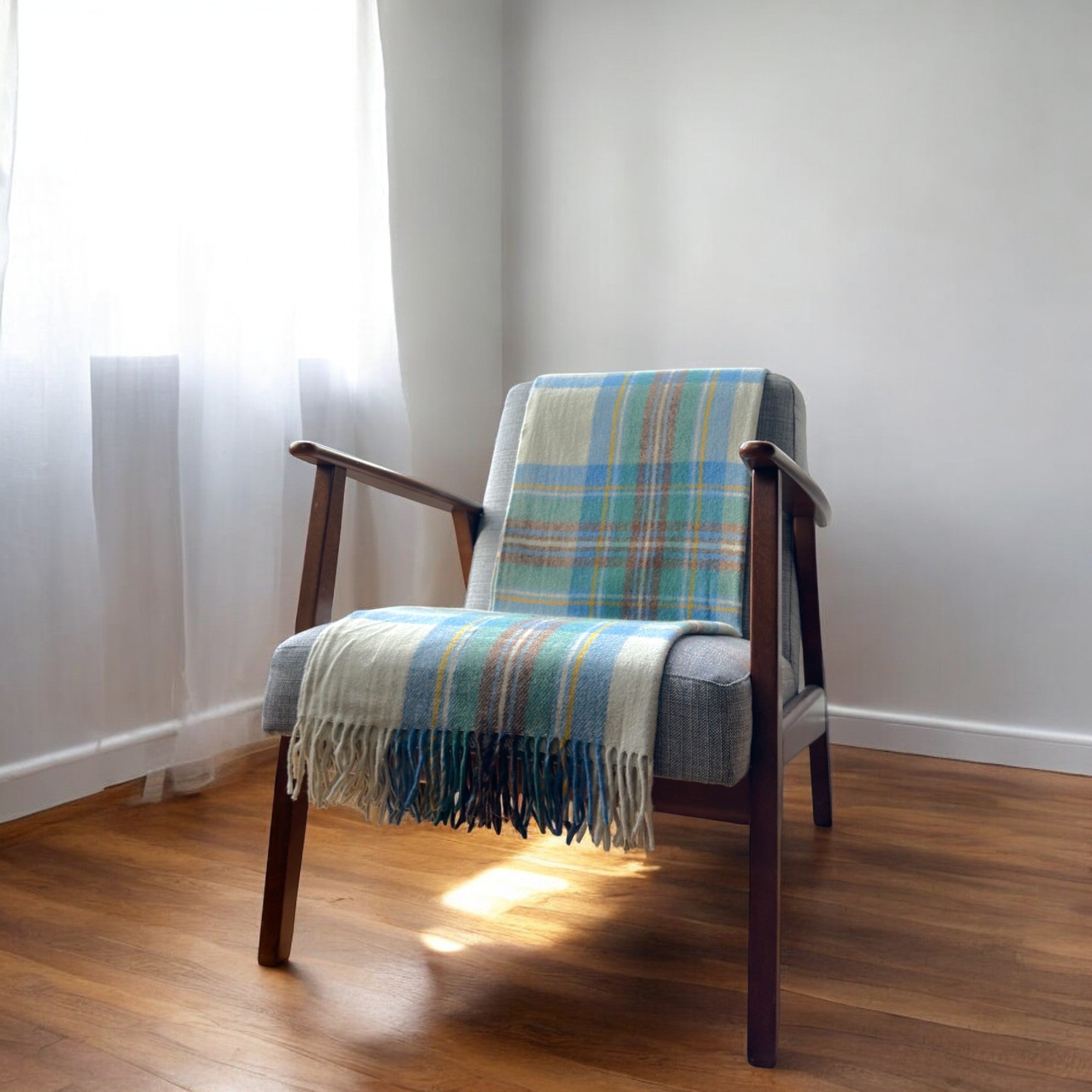 a 100% recycled blanket in stewart muted blue tartan draped over a chair in a cosy room