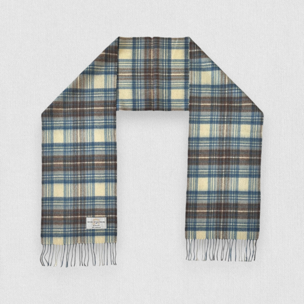 A Stewart Muted Blue tartan scarf made of 100% lambswool, displayed flat with fringes, showing the pattern of blue, grey, and white checkers.