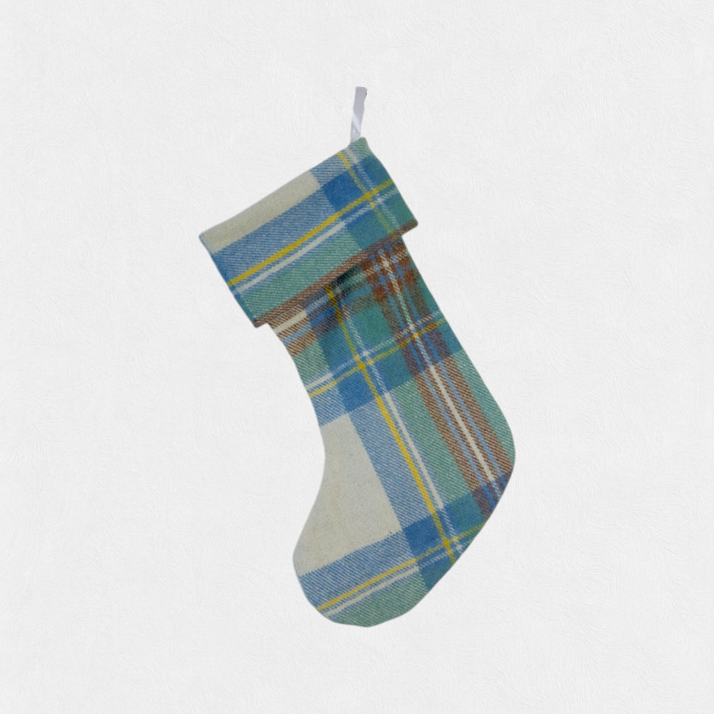 The stewart muted blue tartan christmas stocking hanging on a hook with a white background.