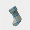 The stewart muted blue tartan christmas stocking hanging on a hook with a white background.