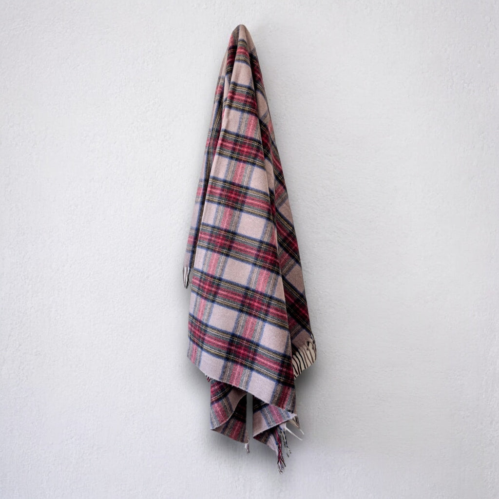 a 100% recycled blanket in stewart dress tartan hanging from a wall hook on a white background 