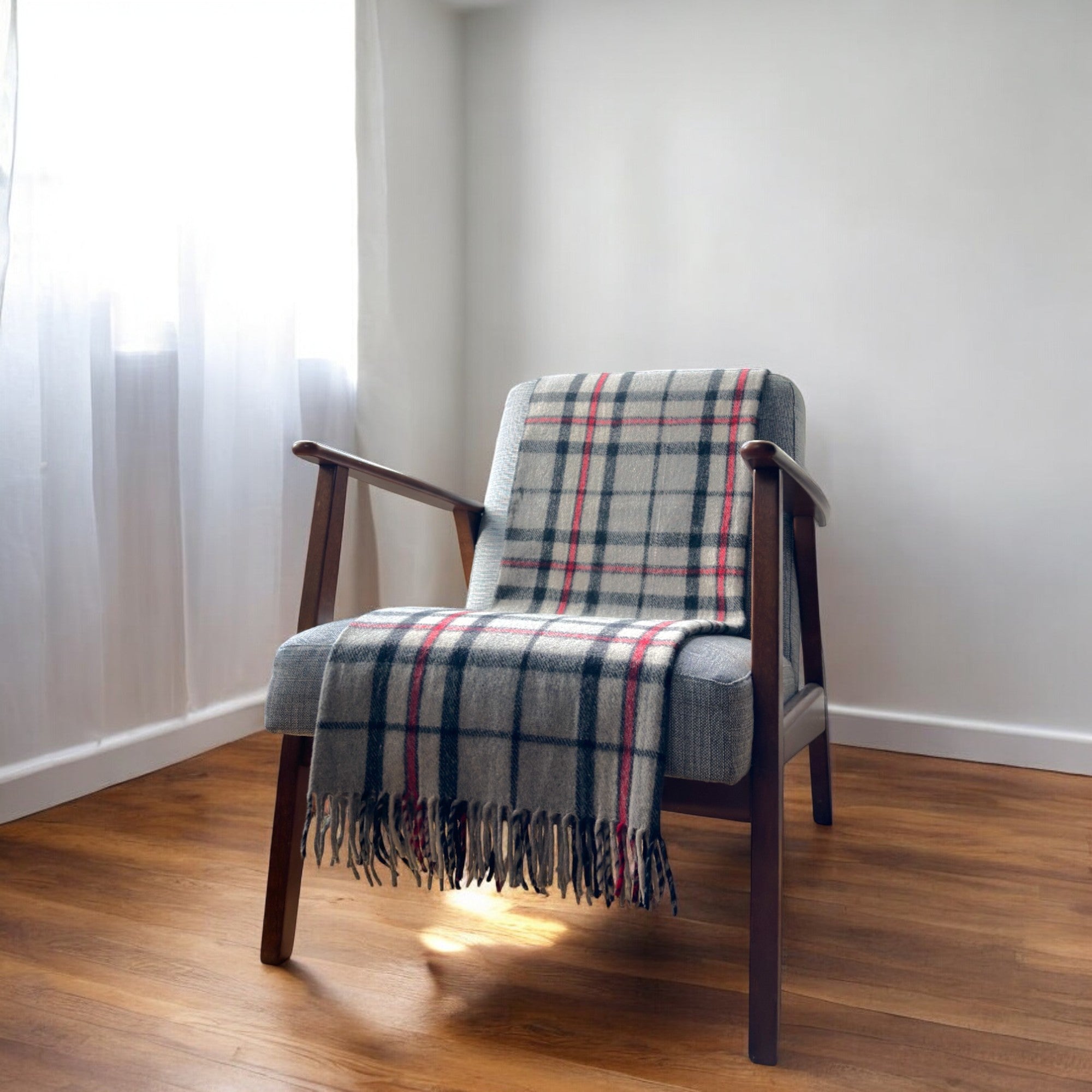 a 100% recycled blanket in thomson grey tartan draped over a chair in a cosy room
