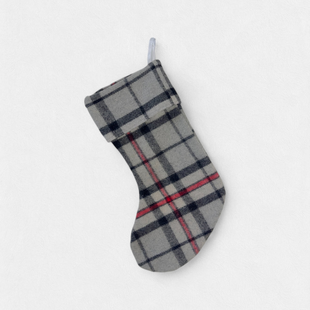 The Thomson Grey 100% wool Christmas Stocking hanging. from a hook with a white background.