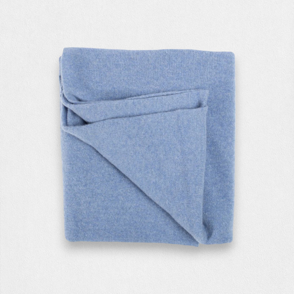 A folded denim blue cashmere wrap on a plain background.