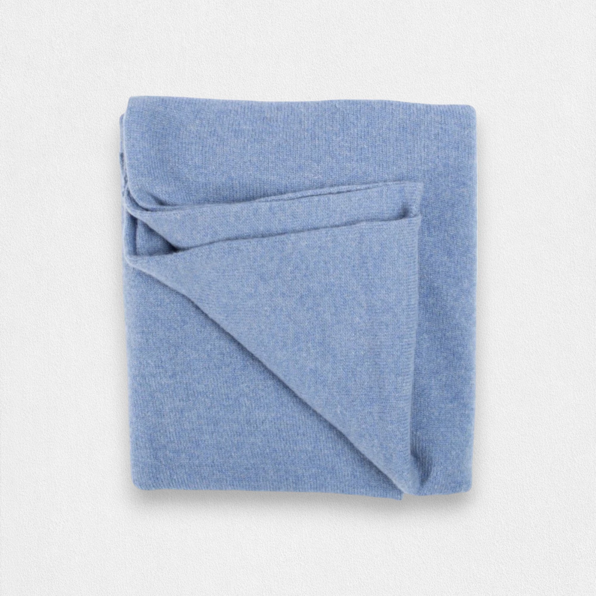 A folded denim blue cashmere wrap on a plain background.
