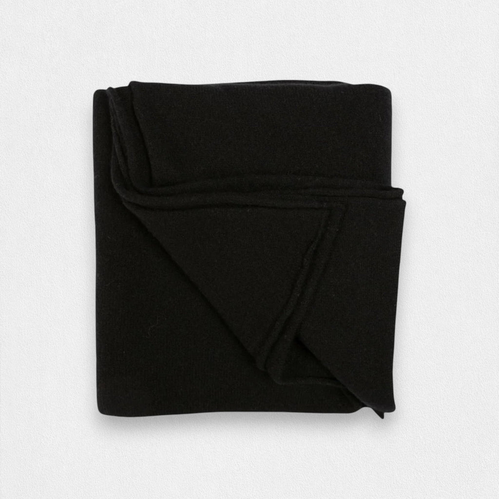 A folded black cashmere wrap on a plain background.