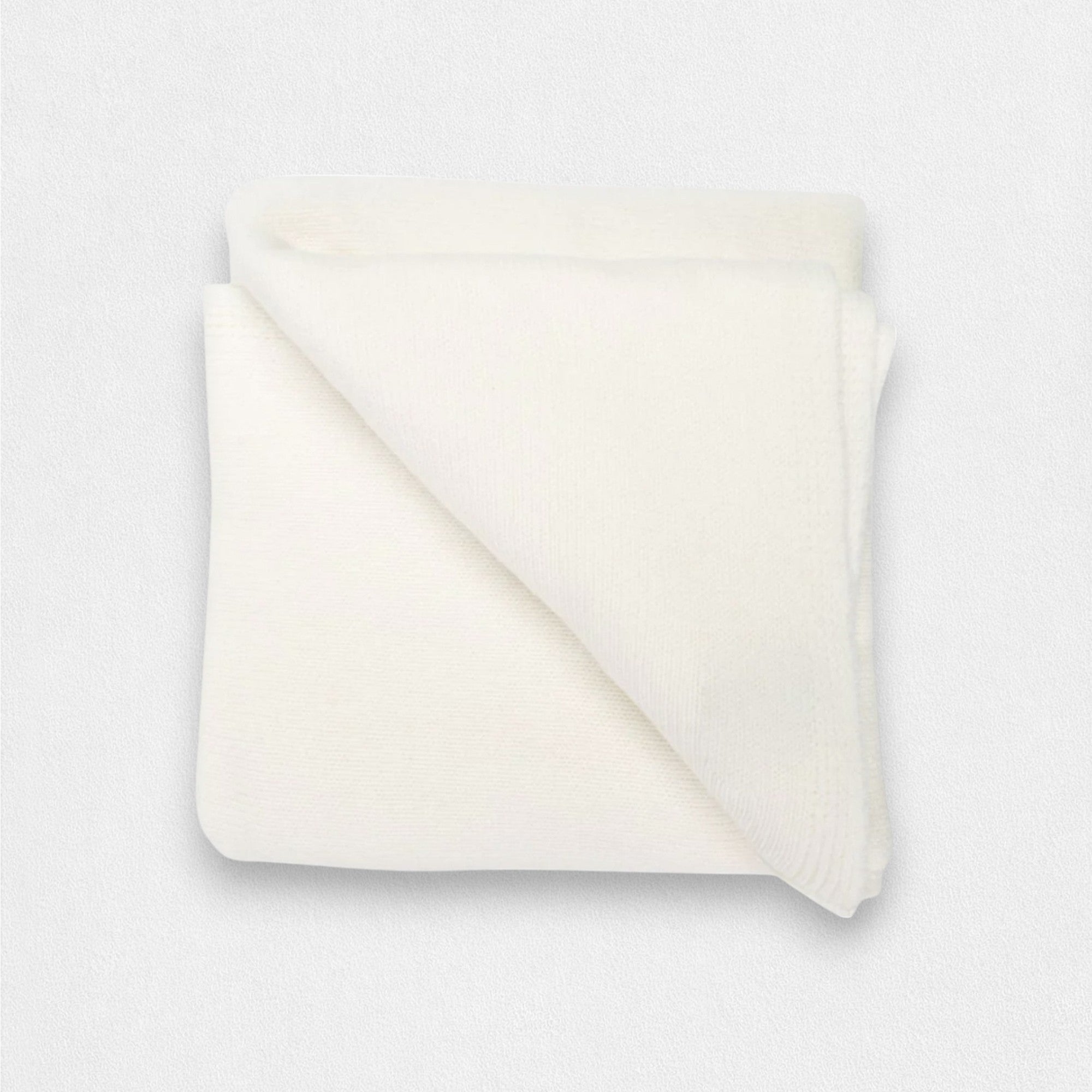 A folded white cashmere blanket on a plain background.