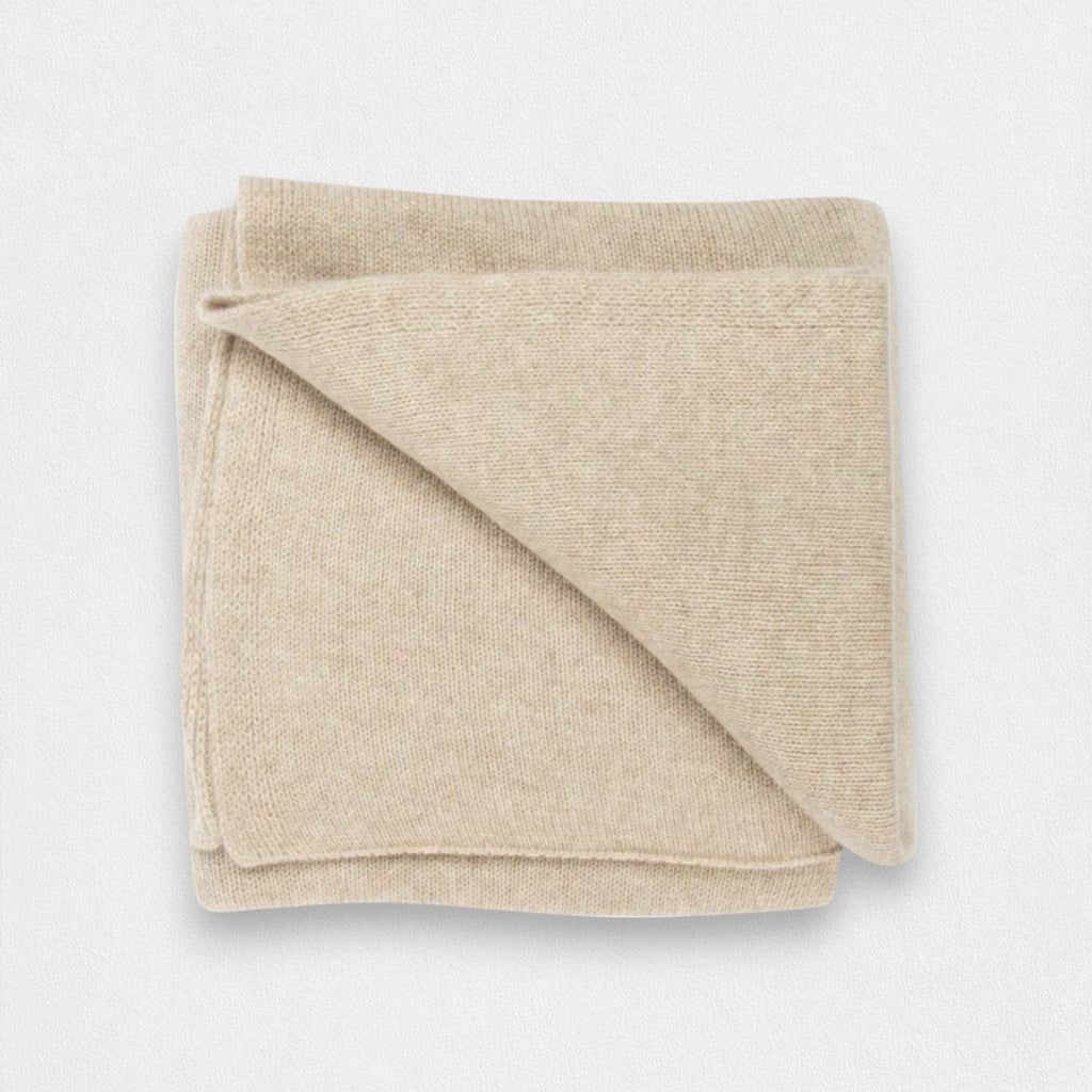 A natural cream colored 100% cashmere blanket folded neatly.